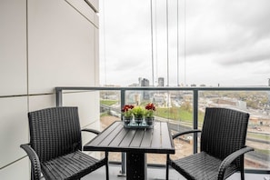En balkong med ett bord och två stolar, med utsikt över stadsbilden.