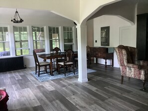 Comedor con mesa y sillas de madera, candelabro y ventanas amplias.