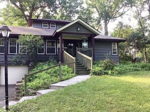 A two-story house with a front porch, a staircase, and a well-maintained lawn.