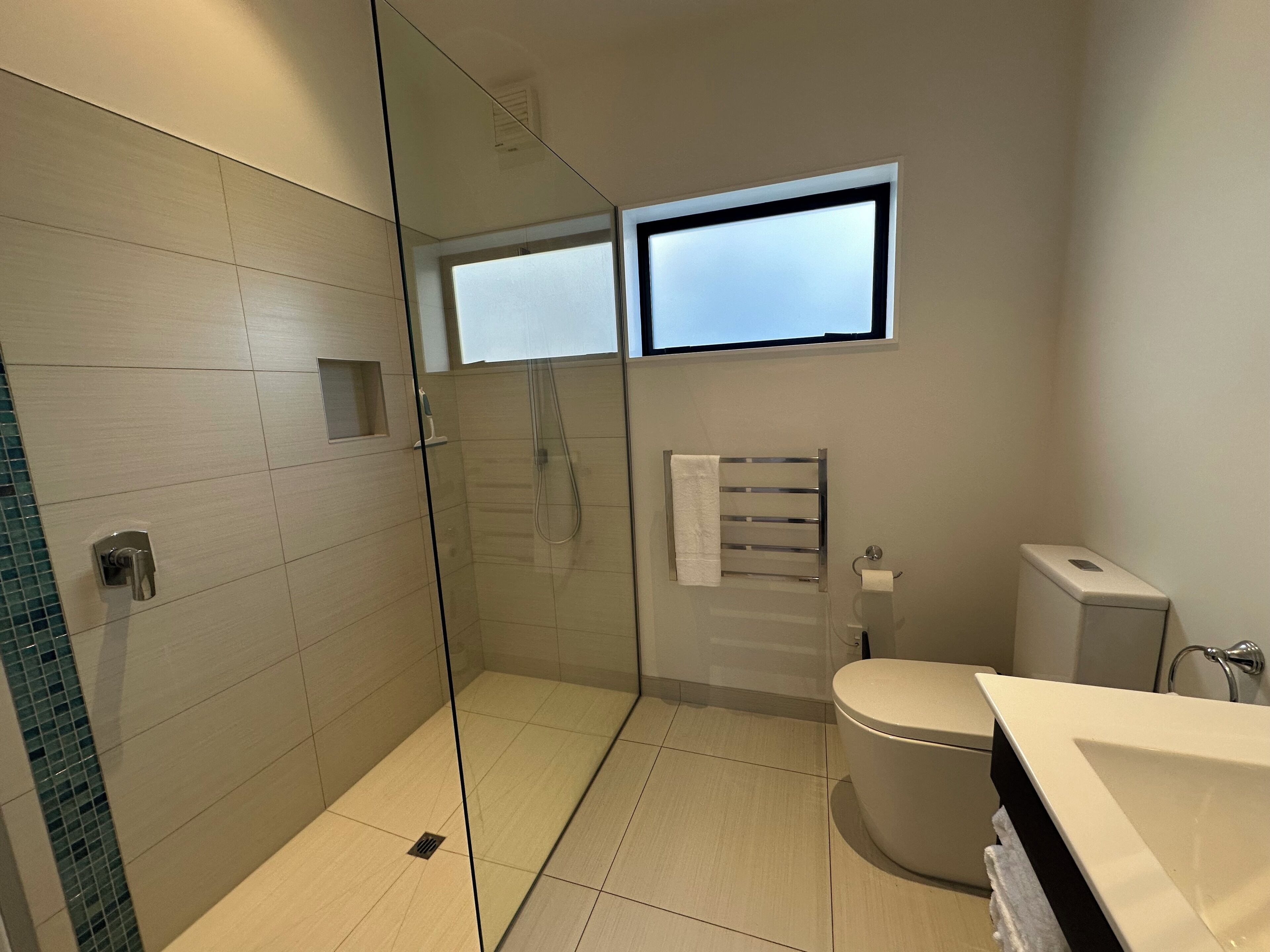 A modern bathroom with a glass-enclosed shower, a toilet, and a sink.