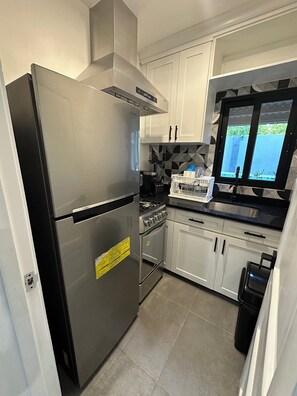 Una cocina moderna con electrodomésticos de acero inoxidable, armarios blancos y una ventana con vistas.