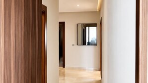 A hallway with a wooden panel wall, a mirror, and a tiled floor. - Exclusive apartment with stunning panoramic sea views (Tanger)