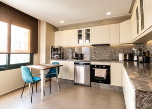 A modern kitchen with a dining area, stainless steel appliances, and a granite countertop. - Exclusive apartment with stunning panoramic sea views (Tanger)