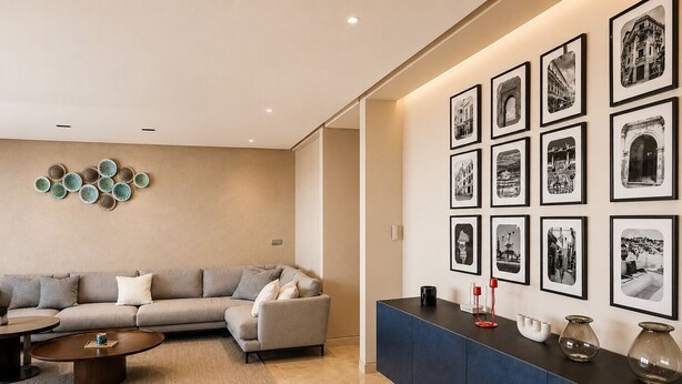 A modern living room with a sofa, coffee table, and a wall decorated with framed photographs. - Exclusive apartment with stunning panoramic sea views (Tanger)