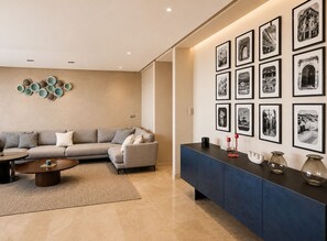 A modern living room with a sofa, coffee table, and a wall decorated with framed photographs. - Exclusive apartment with stunning panoramic sea views (Tanger)