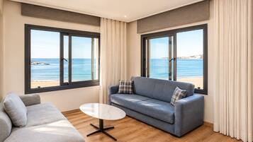 Een moderne woonkamer met een bank, een salontafel en grote ramen met uitzicht op het strand.