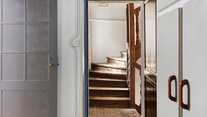 Uma escadaria leva a um patamar com uma porta à esquerda.