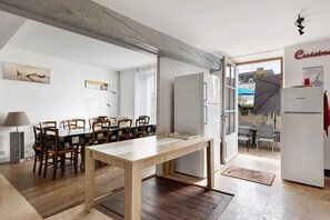 Una zona de menjador amb taula i cadires de fusta, un frigorífic i vista exterior.