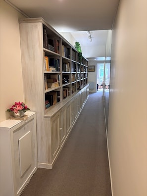 A hallway with a long bookshelf filled with books, a radiator, and a potted plant. - Spacious Recoleta apartment in desired location - French style & Modern Comfort (Buenos Aires)
