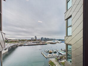 A view of a waterfront with a bridge, boats, and buildings in the background. - Modern Waterfront Condo with Harbour Views (Victoria Central British Columbia Provincial Government)