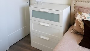A bedroom with a white dresser, a round mirror, and a bed with a patterned pillow. - Modern Waterfront Condo with Harbour Views (Victoria Central British Columbia Provincial Government)