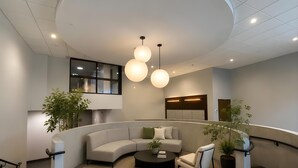 A modern interior with a curved sofa, a round coffee table, and a potted plant. - Modern Waterfront Condo with Harbour Views (Victoria Central British Columbia Provincial Government)
