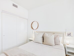 A bedroom with a bed, bedside tables, a mirror, and a door. - Modern Waterfront Condo with Harbour Views (Victoria Central British Columbia Provincial Government)
