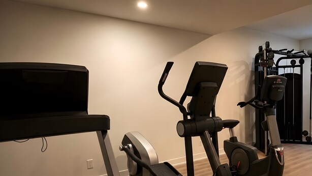 A home gym with a treadmill, elliptical, and weight machine. - Modern Waterfront Condo with Harbour Views (Victoria Central British Columbia Provincial Government)