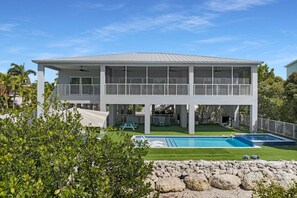 A two-story house with a pool, covered outdoor seating, and a fenced yard.