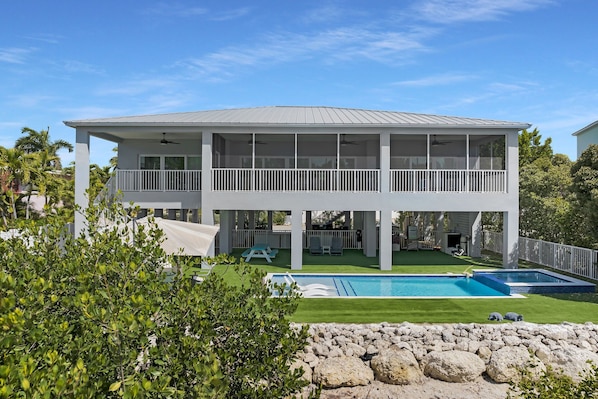 A two-story house with a pool, covered outdoor seating, and a fenced yard.