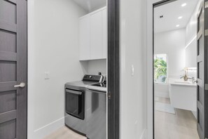 A compact kitchen with a built-in oven and microwave, white cabinets, and a view of a bathroom through an open door. - Treasure Cove- Stunning 5-bedroom, Pool Home-Walking distance to Sombraro Beach (Marathon)