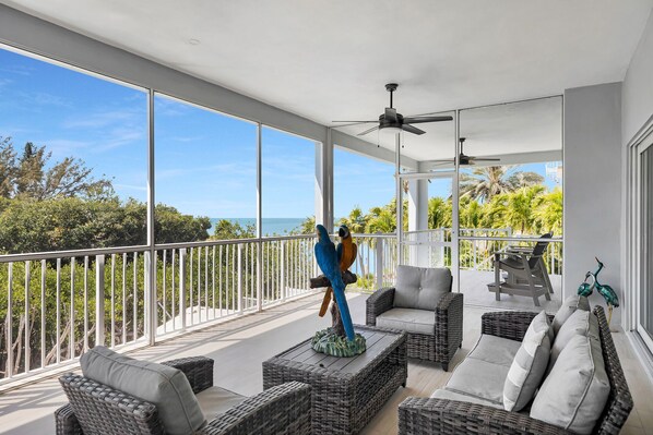A balcony with wicker furniture, a ceiling fan, and a view of the ocean.