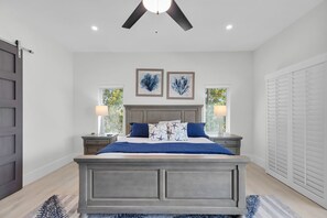 A bedroom with a bed, nightstands, a ceiling fan, and artwork on the wall.