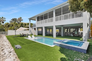 A two-story house with a swimming pool, outdoor seating, and a covered patio area.