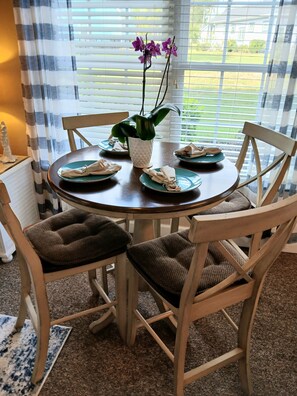 A dining table with plates, napkins, and a potted plant. - Prime Sea Trail condo. 1st floor end unit-villa and suite combined.  Remodeled! (Sunset Beach)