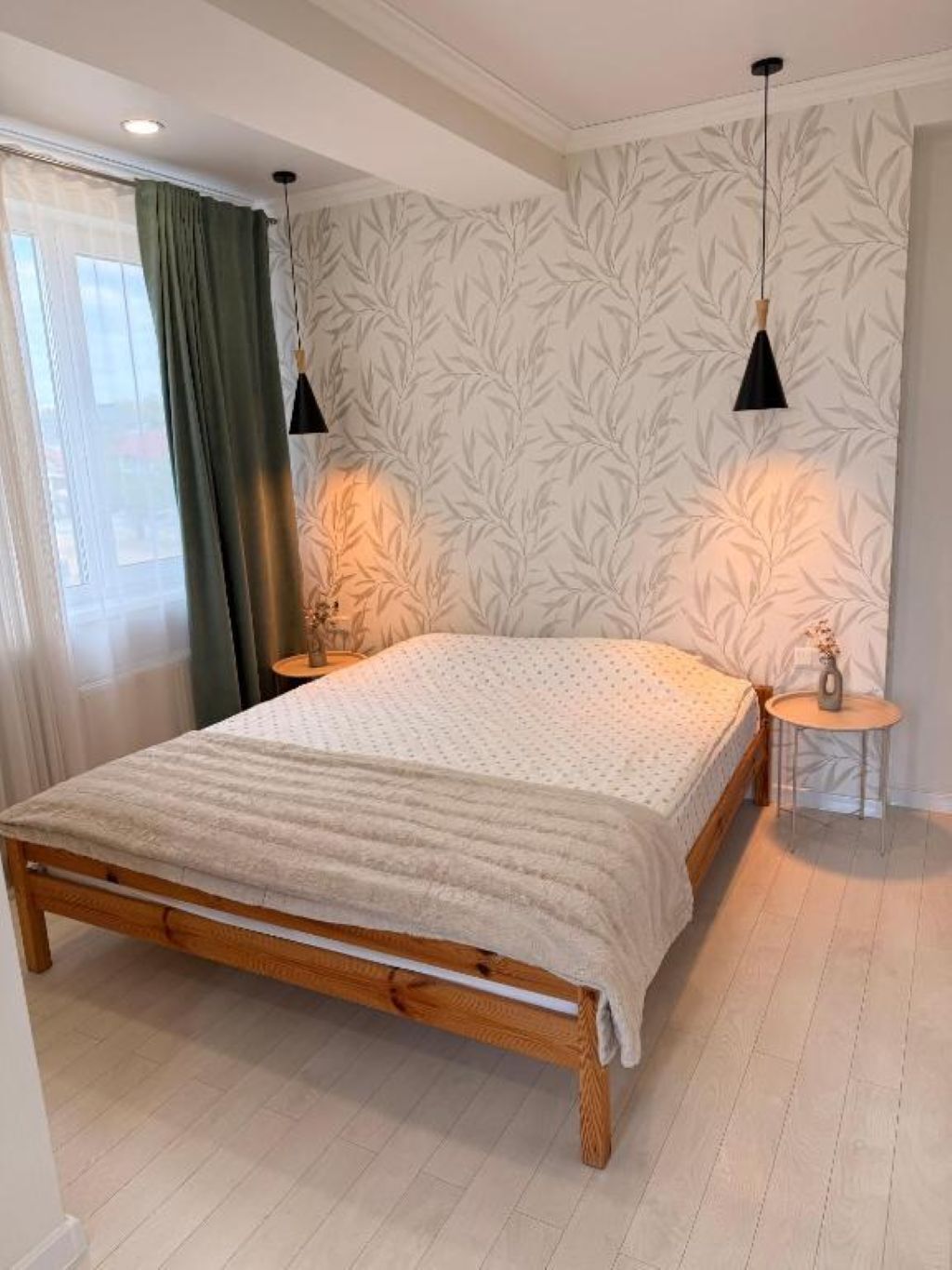 Una camera da letto con un letto in legno, due comodini, una finestra con tende e un muro decorato con un motivo a foglia.