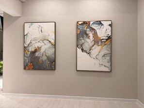 Two abstract paintings on a plain wall in a room with a light-colored floor. - Stylish Apartment near City Center (Chișinău)