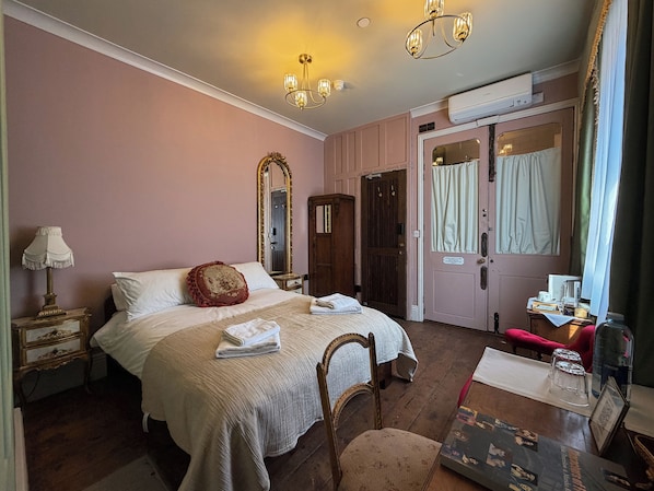 A bedroom with a bed, a mirror, a dresser, a chair, and a table with a picture frame. - 41 Whitfield Street (London)