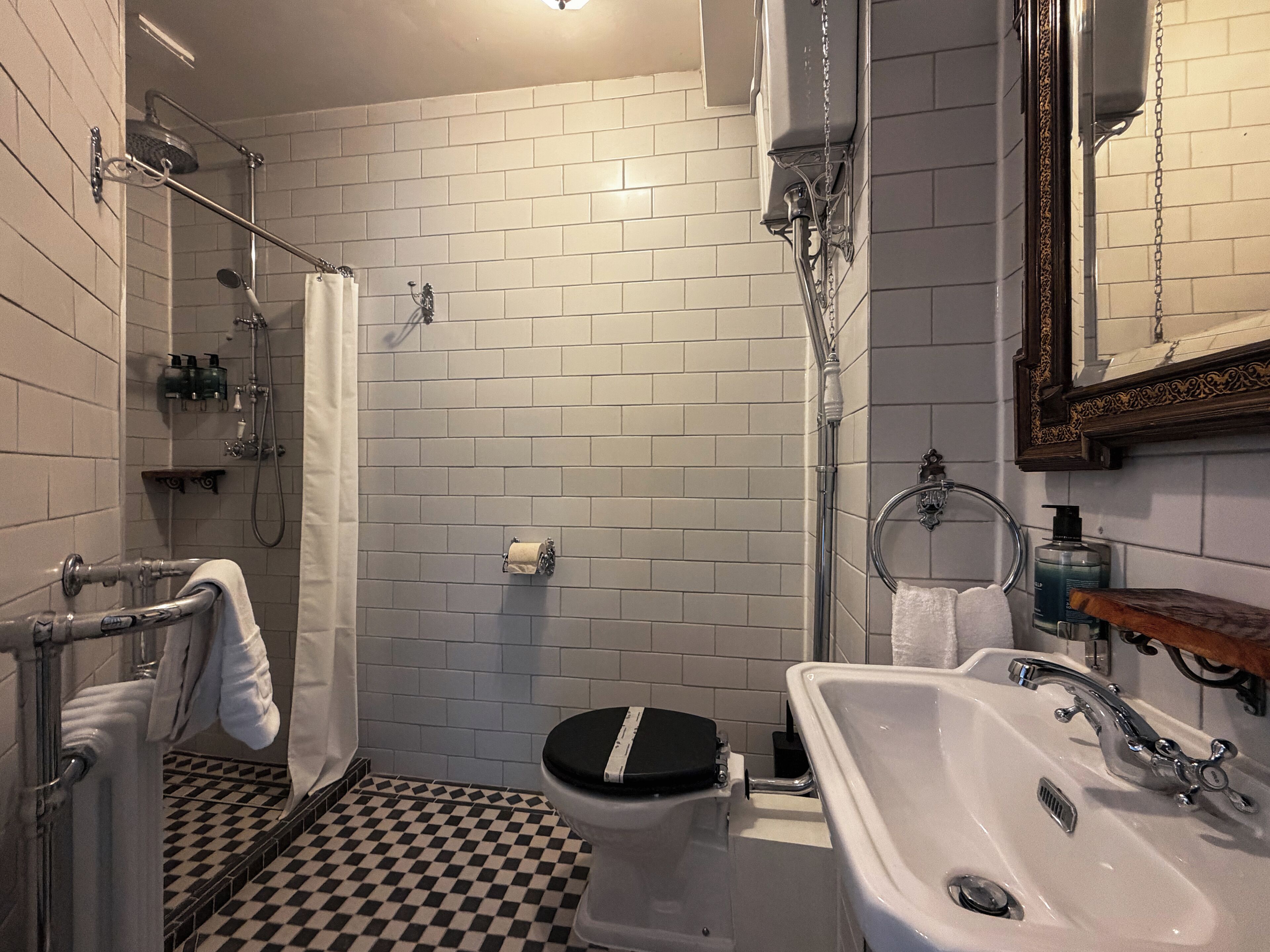 Un baño con piso a cuadros, inodoro, lavabo y ducha.