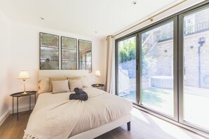 Ein Schlafzimmer mit einem großen Bett, zwei Nachttischen mit Lampen, Blick auf einen Innenhof durch eine Schiebetür und einer an der Wand hängenden Karte.