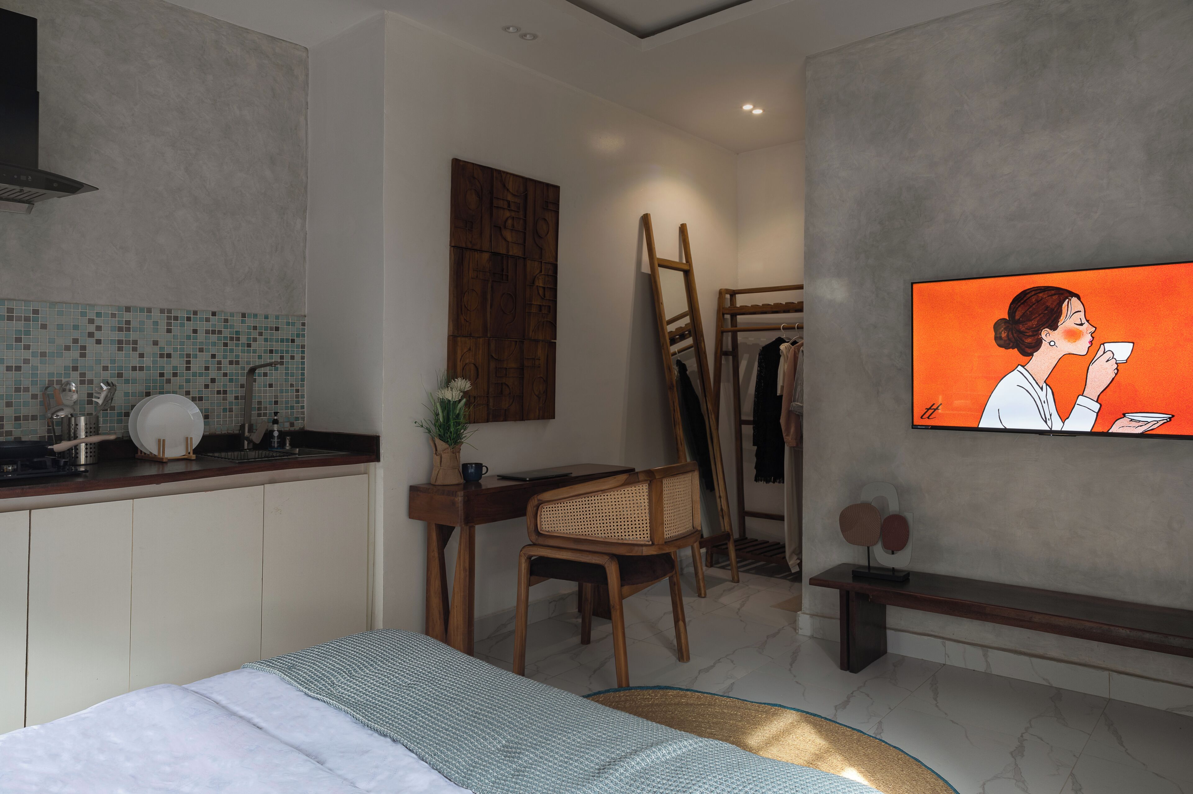 A modern bedroom with a bed, a desk, a chair, a TV, and a wardrobe.