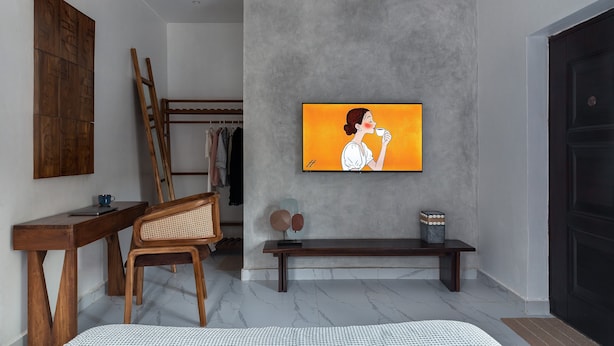 Ein modernes Interieur mit einer grauen Betonwand, einem Holzstuhl, einer Bank und einem gerahmten Kunstwerk.