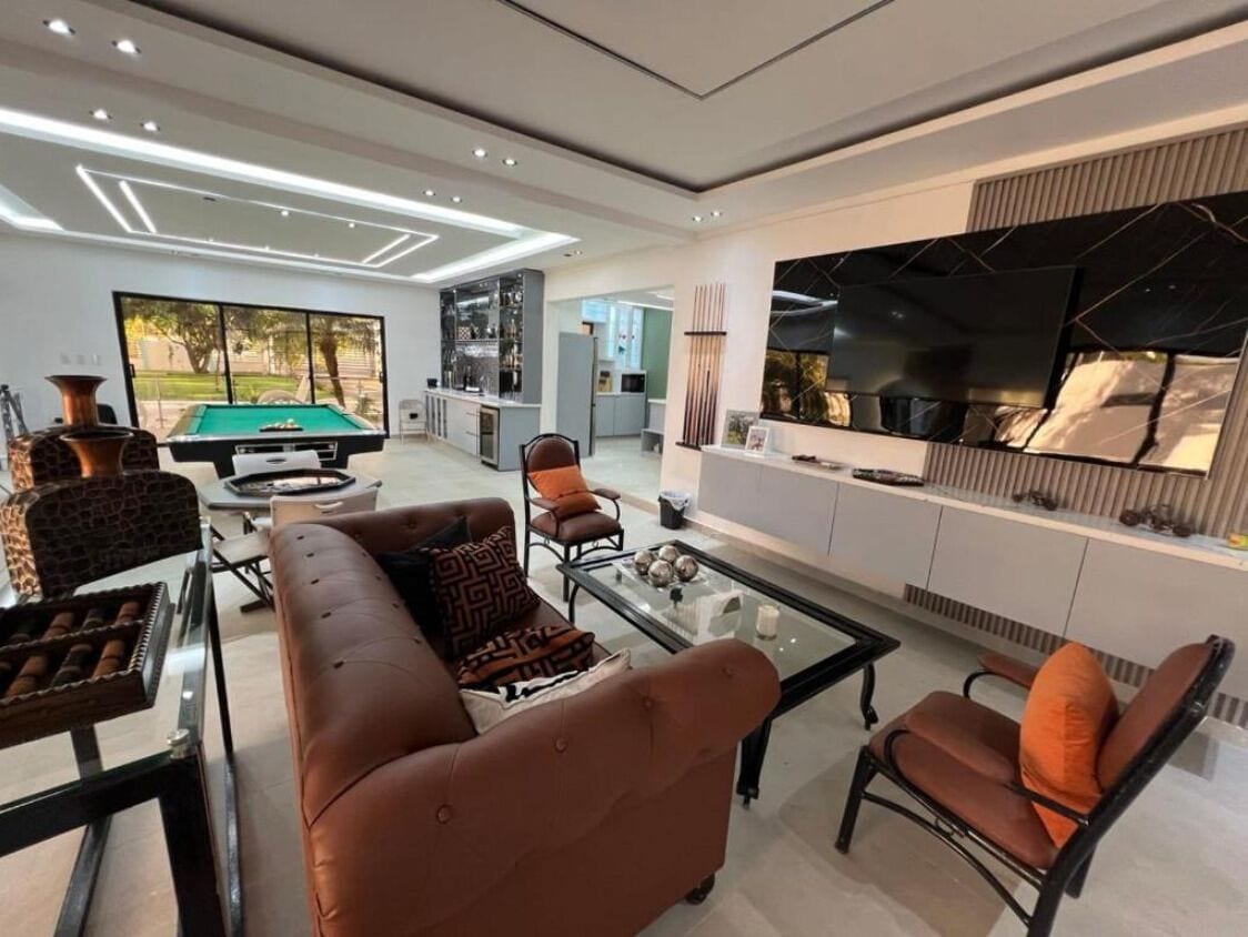 A modern living room with a pool table, leather sofas, and a flat-screen TV.