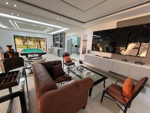 Una sala moderna con mesa de billar, sofás de cuero y televisor de pantalla plana.