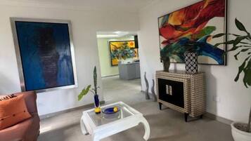 Un salon moderne avec un canapé, une table basse et des œuvres d’art accrochées aux murs.