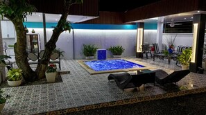 An outdoor patio with a pool, seating area, and potted plants.
