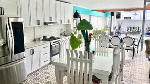 A modern kitchen with white cabinets, a dining table with chairs, and a patterned floor.