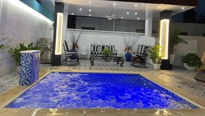 An outdoor pool area with a hot tub, seating, and potted plants.