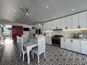 A modern kitchen with white cabinets, a dining table with chairs, and a patterned floor.