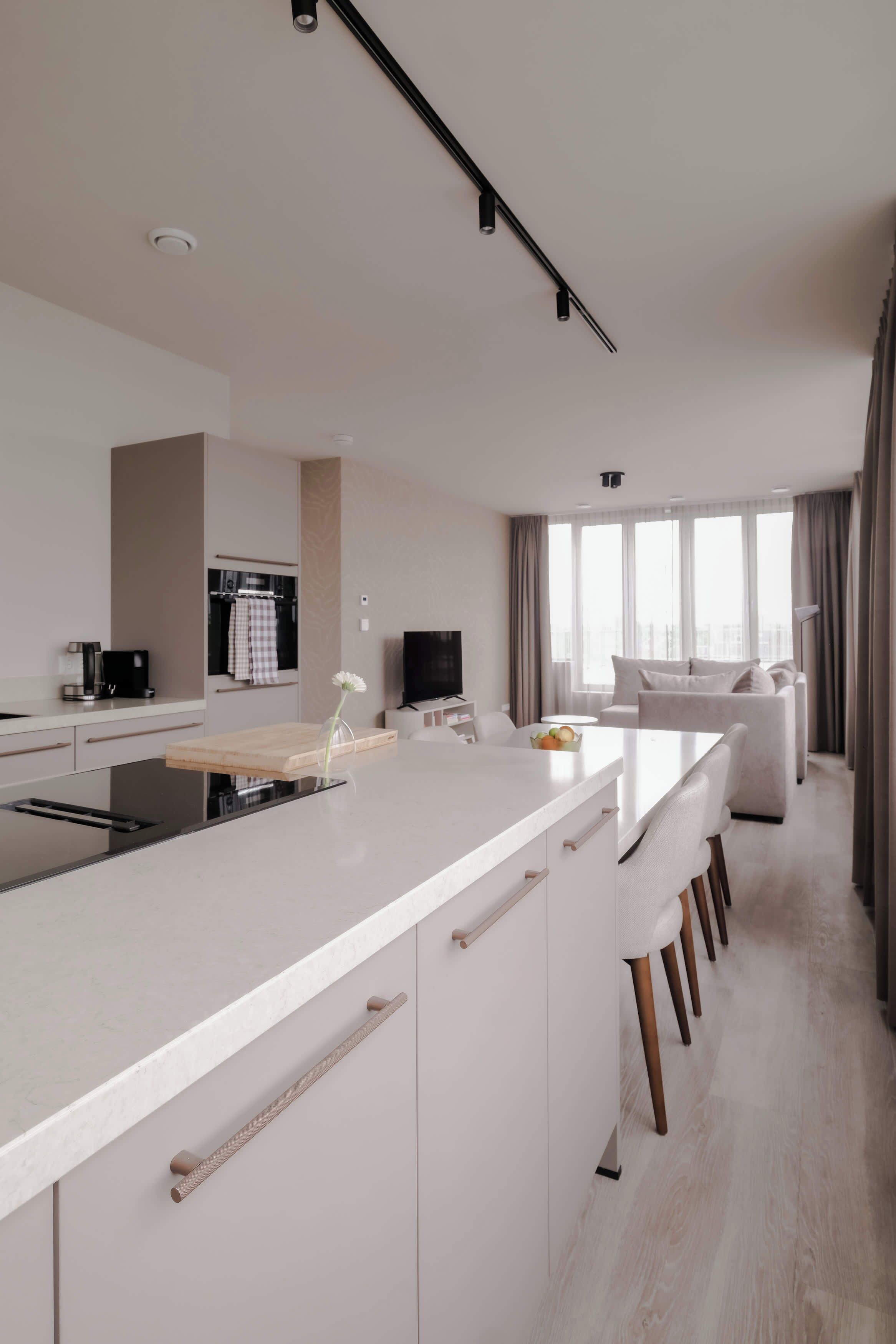 Una cocina moderna con una isla central, un rincón comedor con sofá y vistas a la ciudad a través de amplios ventanales.