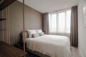 Ein modernes Schlafzimmer mit einem großen Bett, einem Nachttisch und einem Fenster mit Vorhängen.