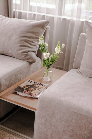 A modern living room with a beige sofa, a small table with a magazine, and a vase with flowers. - 2BR Rooftop Terrace in Rotterdam City Centre (Rotterdam)