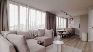 A modern living room with a sofa, a coffee table, and a dining area with chairs and a table. - 2BR Rooftop Terrace in Rotterdam City Centre (Rotterdam)