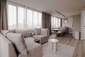A modern living room with a sofa, a coffee table, and a dining area with chairs and a table. - 2BR Rooftop Terrace in Rotterdam City Centre (Rotterdam)