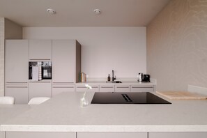 A modern kitchen with a central island, built-in appliances, and a minimalist design. - City Center Penthouse w/ Free Parking & City Views (Rotterdam)