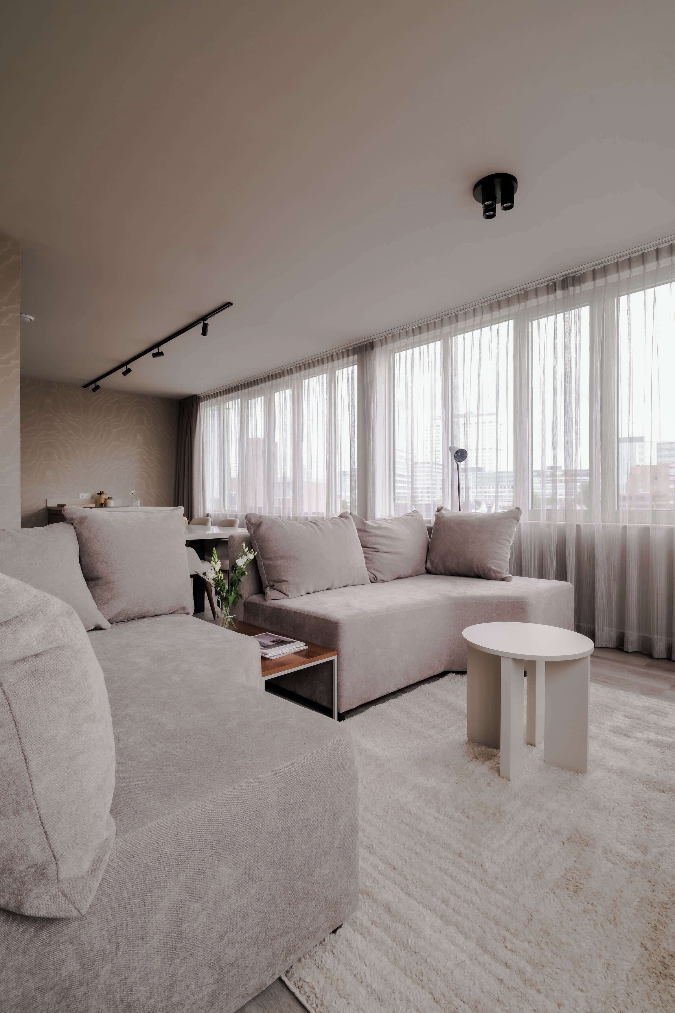 A modern living room with a large sectional sofa, a coffee table, and a round side table.