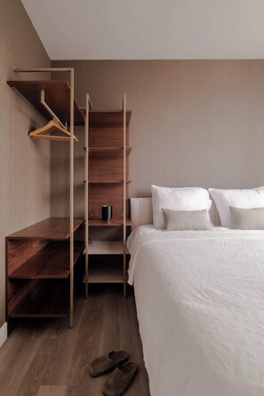 A bedroom with a bed, a wooden wardrobe, and a pair of slippers on the floor. - 2BR Penthouse Rotterdam City Centre (Rotterdam)