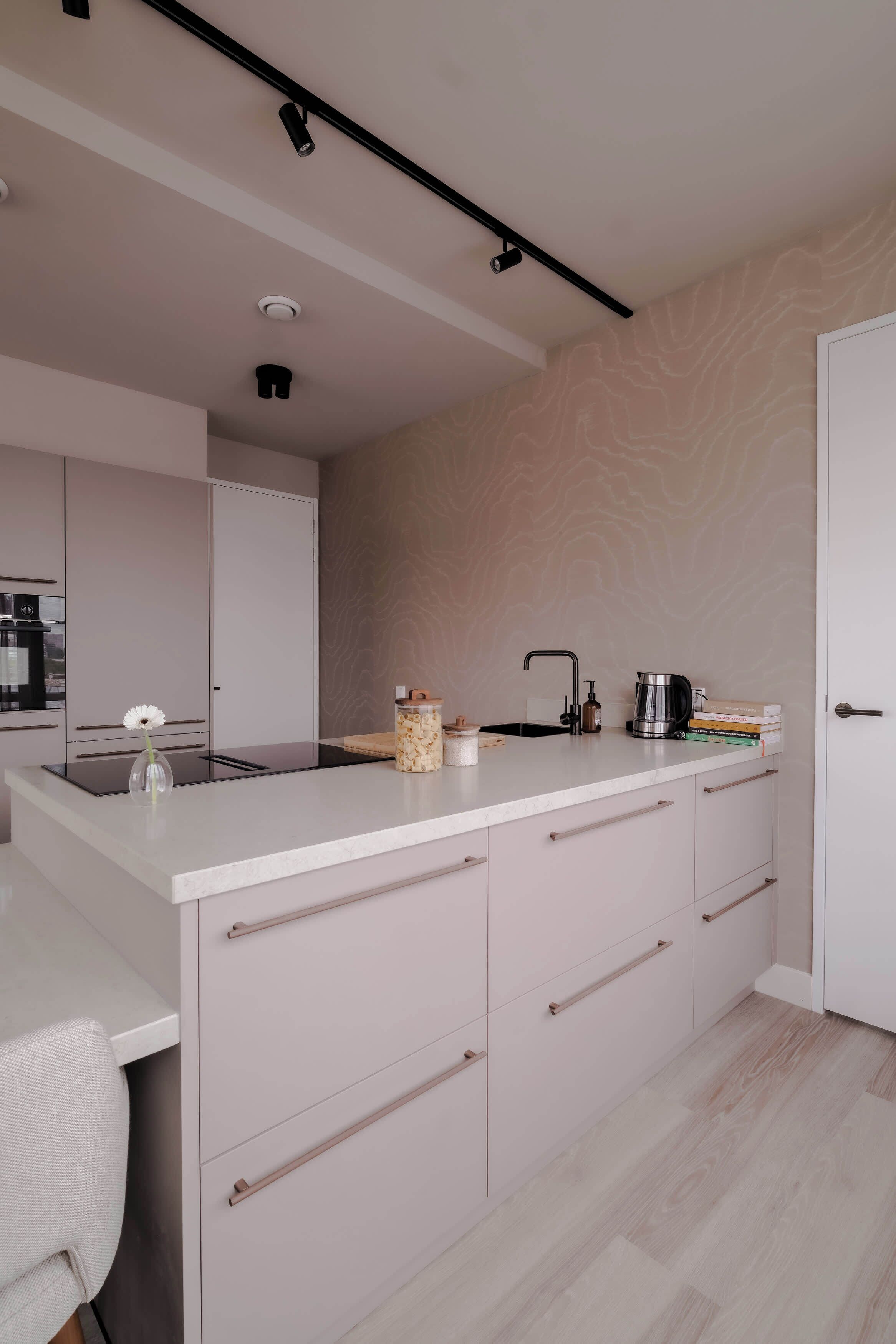 A modern kitchen with a central island, white cabinetry, and a patterned wall.