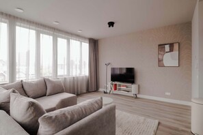A modern living room with a sofa set, a flat-screen TV, and a patterned wall. - 2BR Penthouse Rotterdam City Centre (Rotterdam)