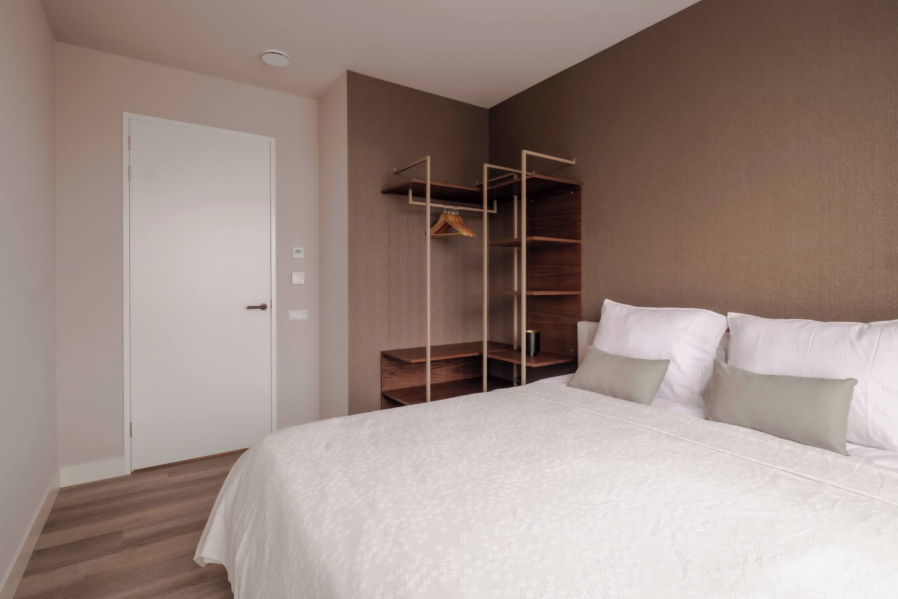 A bedroom with a bed, a wardrobe, and a door.